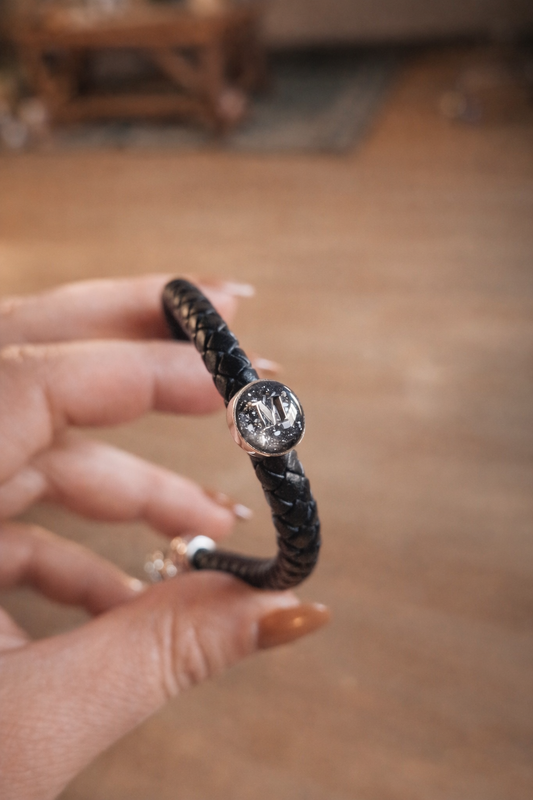 Bracelet homme en cuir noir avec cabochon en argent forgé renfermant des cendres, bijou souvenir artisanal signé Étreinte Éternelle.