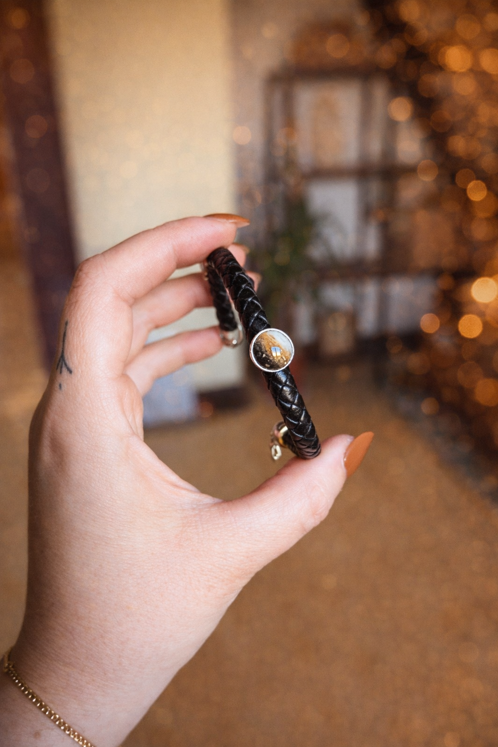 Main tenant le bracelet souvenir Memorys pour homme, en cuir noir tressé avec cabochon en résine renfermant des poils d’animal, bijou commémoratif Étreinte Éternelle.