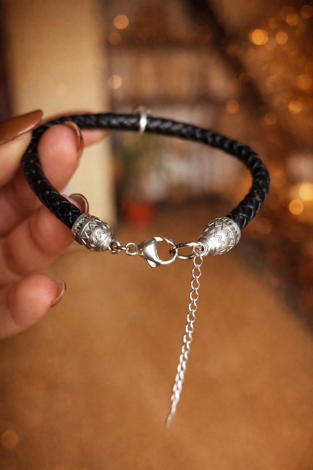 Main tenant le bracelet souvenir Memorys homme, en cuir noir tressé avec cabochon en résine renfermant des poils d'un chien, bijou commémoratif Étreinte Éternelle.