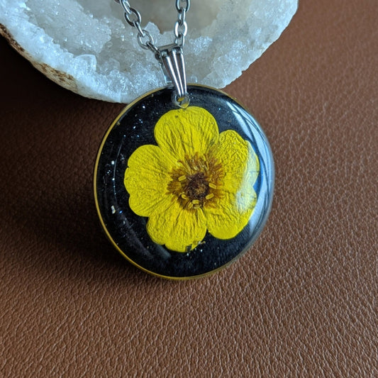 collier bouton d'or jaune sur fond noir et paillettes argentées
