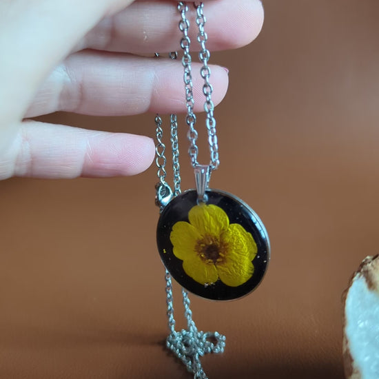 collier bouton d'or jaune sur fond noir et paillettes argentées